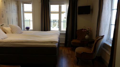 a hotel room with a bed and a chair and a window at Pensionat Ankargården in Öregrund