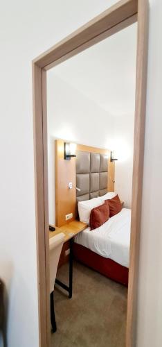 a bedroom with a bed and a desk and a mirror at Hotel de France 18 in Paris