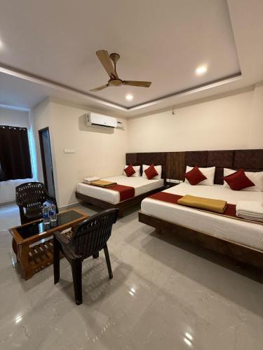 a bedroom with two beds and a table and chairs at Arudra Residency in Tiruvannāmalai