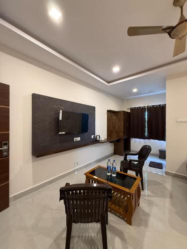 a living room with a tv and a table and chairs at Arudra Residency in Tiruvannāmalai