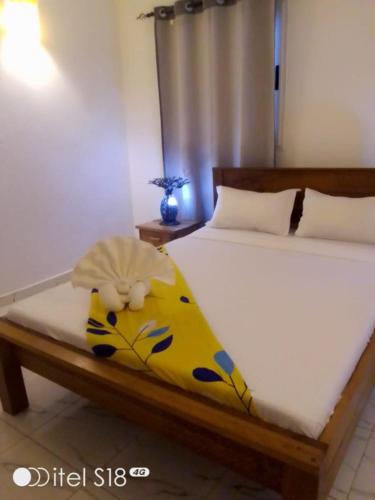 Una cama con una manta amarilla con un animal de peluche. en SummerDreams, en Nosy Be