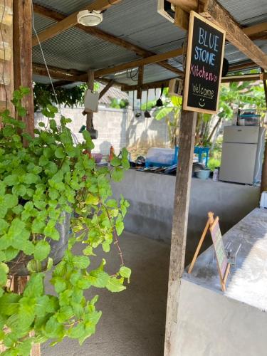 a sign for a blue store with a sign next to a plant at Blue stone in Pai
