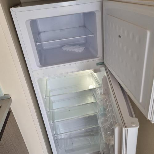 un réfrigérateur vide avec sa porte ouverte dans une cuisine dans l'établissement mobilhome au domaine des iscles emplacement 137, à La Roque-dʼAnthéron
