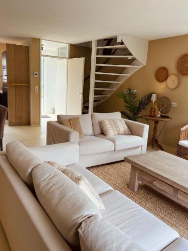 a living room with two white couches and a staircase at Vakantiewoning in villapark de oesterbaai 113 in Wemeldinge