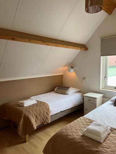a bedroom with two beds and a window at Vakantiewoning in villapark de oesterbaai 113 in Wemeldinge