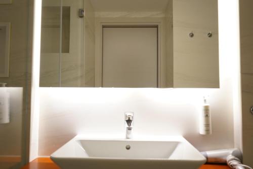 a bathroom with a white sink and a mirror at Bougainville Bay Hotel in Sarandë