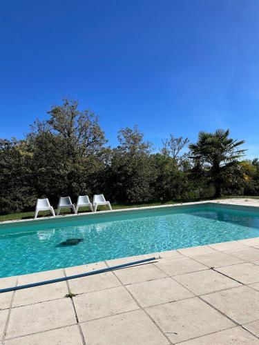 - une piscine avec 2 chaises longues dans l'établissement Maison de campagne avec grande piscine, à Agonac