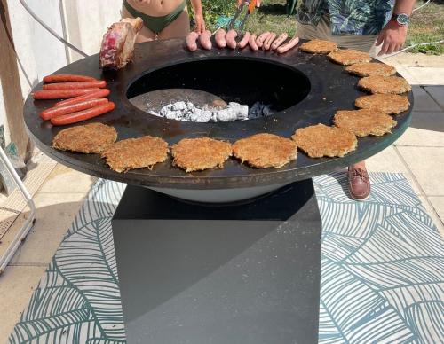 a person is cooking food on a grill at Maison de campagne avec grande piscine in Agonac