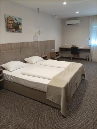a bedroom with a large bed and a desk at Hotel Storia in Čapljina