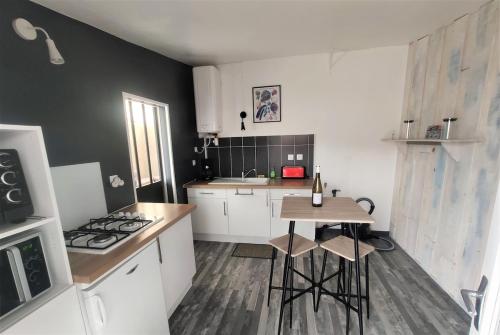 une cuisine avec des armoires blanches, une table et une cuisinière dans l'établissement Maison La Tranche sur Mer - 500m de la plage - 4-5 personnes, à La Tranche-sur-Mer