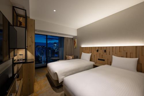 a hotel room with two beds and a window at Miyako City Osaka Hommachi in Osaka