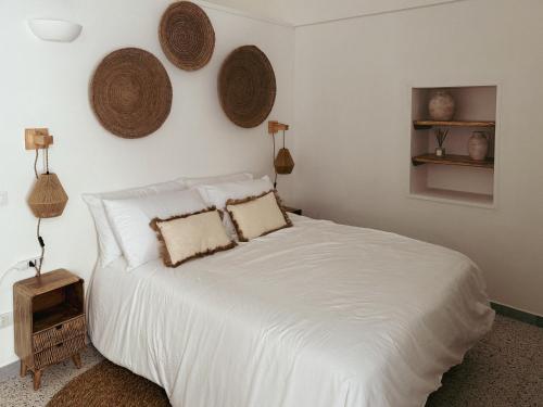 a bedroom with a bed with white sheets and baskets on the wall at Dimora Pinto in Locorotondo