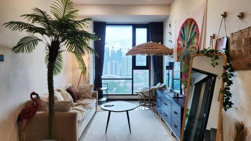 a living room with a couch and a palm tree at Opus Residences Kuala Lumpur by Infini Suites in Kuala Lumpur