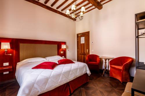 a bedroom with a large bed and two red chairs at Villa Lecchi Hotel Wellness in Colle Val D'Elsa