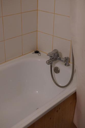 La salle de bains est pourvue d'une baignoire avec un lavabo et un robinet. dans l'établissement Studio cosy Plan Peisey 1600m, à Peisey-Nancroix