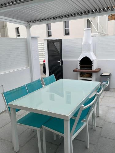 - une table et des chaises sur une terrasse avec un four extérieur dans l'établissement Maison plein centre-ville ménage inclus, à Saint-Hilaire-de-Riez