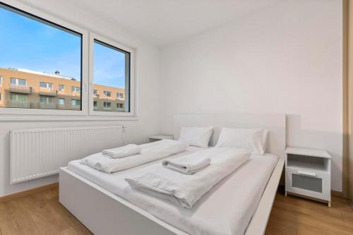 a white bed in a white room with a window at Pressburg Airport Apartment with own parking in Bratislava