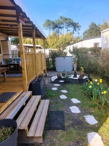 une arrière-cour avec une terrasse et un banc en bois dans l'établissement Mobil Home Denise et Michel, à Lit-et-Mixe