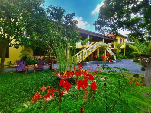 a house with a garden with red flowers in the yard at Villa Romduol in Kampot