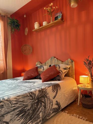 - une chambre avec des murs rouges et un lit avec des oreillers dans l'établissement Maison paisible, à Niort