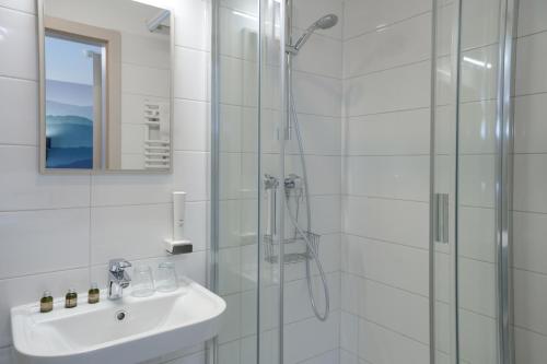 a white bathroom with a shower and a sink at Gasthaus Panzió in Szilvásvárad