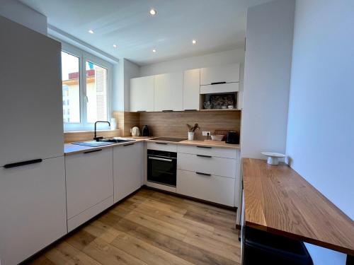 une cuisine avec des armoires blanches et un plancher en bois dans l'établissement Charmant appartement 50 m Plage, à Ajaccio