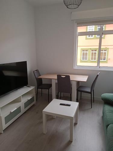 a living room with a table and a tv at Entresuelo luminoso cerca de Escaño in Ferrol