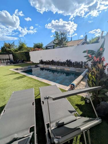 - une piscine avec 2 chaises longues dans l'établissement Maison de vacances avec piscine, calme et confort, à Béziers