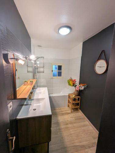 une salle de bain avec une baignoire, un lavabo et un miroir dans l'établissement Maison de vacances avec piscine, calme et confort, à Béziers