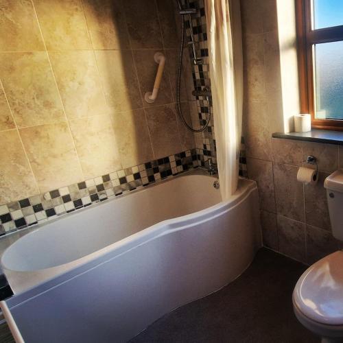 a bathroom with a tub and a toilet at Church View House F56H977 in Gorteen