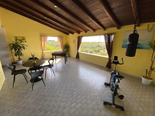 a living room with a table and chairs and windows at Villa Medusa in Tre Fontane