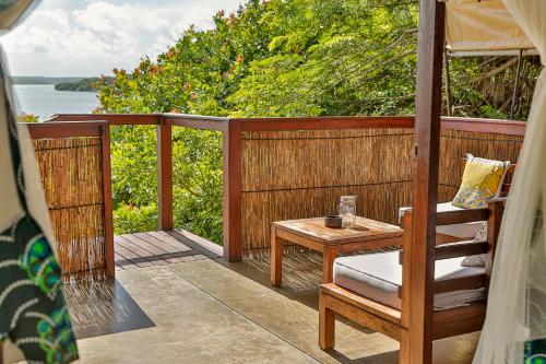 a wooden porch with a table and a chair at Naara Eco Lodge & Spa in Chidenguele