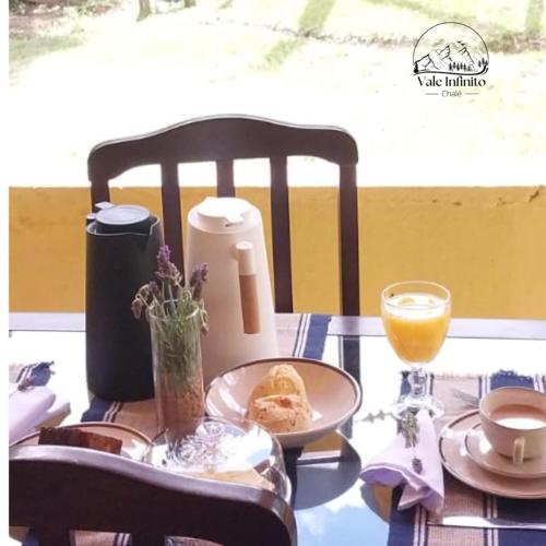 a table with a plate of food and a glass of orange juice at Vale Infinito Chalé in Córrego do Bom Jesus