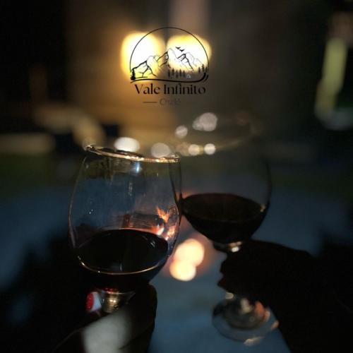 two glasses of red wine sitting on a table at Vale Infinito Chalé in Córrego do Bom Jesus