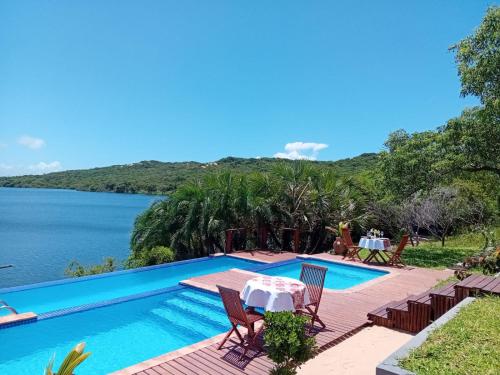 a swimming pool with a table and chairs next to the water at Naara Eco Lodge & Spa in Chidenguele