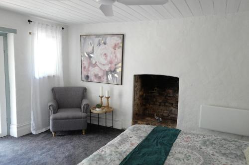 ein Schlafzimmer mit einem Bett und einem Stuhl und einem Kamin in der Unterkunft Charming Historical Cottage in Bridgewater in Bridgewater