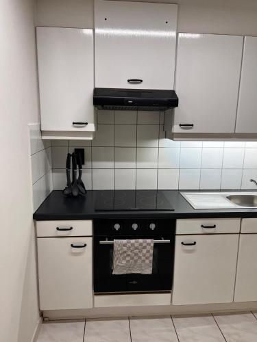 a kitchen with white cabinets and a black stove top oven at Appartement ' Tintin Travels' in Geel