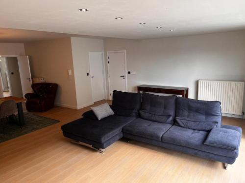 a living room with a blue couch and a table at Appartement ' Tintin Travels' in Geel