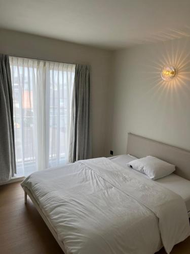 a bedroom with a white bed and a window at Appartement ' Tintin Travels' in Geel
