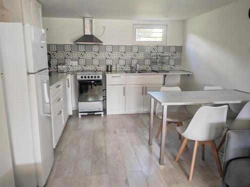 une cuisine avec des armoires blanches et une table avec des chaises dans l'établissement Appartement Le Maro, à Saubusse