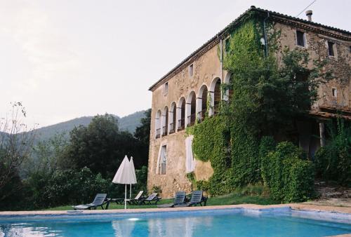 a building with a swimming pool and an umbrella at Casa Rural Mas Garganta in La Pinya