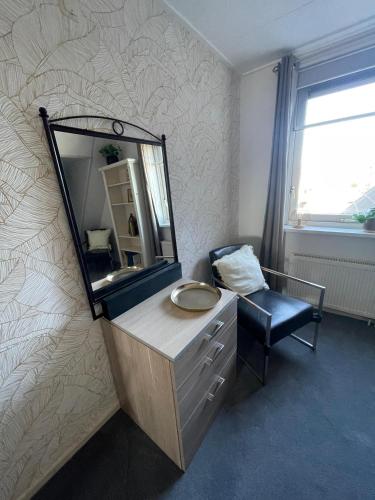 a bathroom with a mirror and a sink and a chair at Hotelkamer de Loft in Anjum