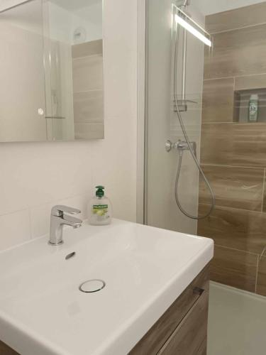 ein weißes Badezimmer mit Waschbecken und Dusche in der Unterkunft Les Hauts de Balaruc THERMES in Balaruc-les-Bains