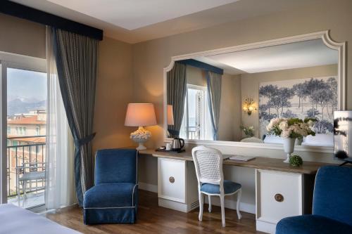 a bedroom with a vanity with a mirror and blue chairs at Palace Hotel in Viareggio