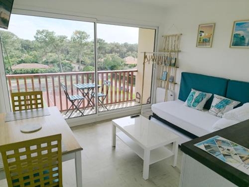a living room with a couch and a balcony at Studio les mouettes in Mimizan-Plage