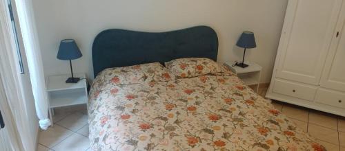 a bedroom with a bed with a floral bedspread and two lamps at Casa Noemi, nel cuore di Varazze, ad un passo dal mare in Varazze