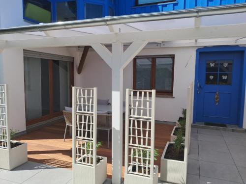 a house with a blue door and two white trellises at Ferienwohnung Sophie - perfekt mit Kind und Kegel in Eitelborn