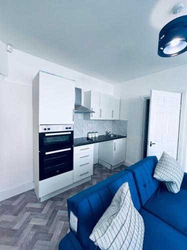 a living room with a blue couch and a kitchen at The Corner house in Hartlepool
