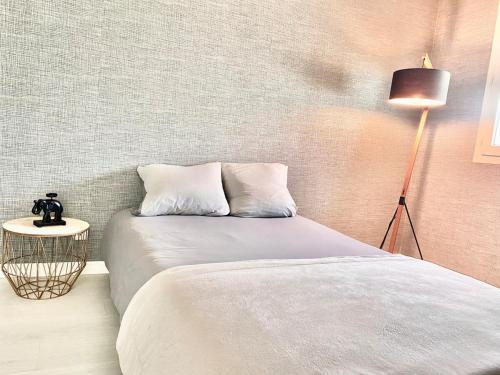 Cette chambre comprend un lit avec deux oreillers et une lampe. dans l'établissement Toison avec piscine, à Dijon