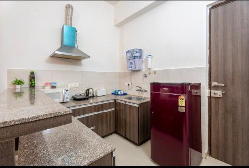 a kitchen with a red refrigerator and a counter at The Label Stay Skyscraper in Gurgaon